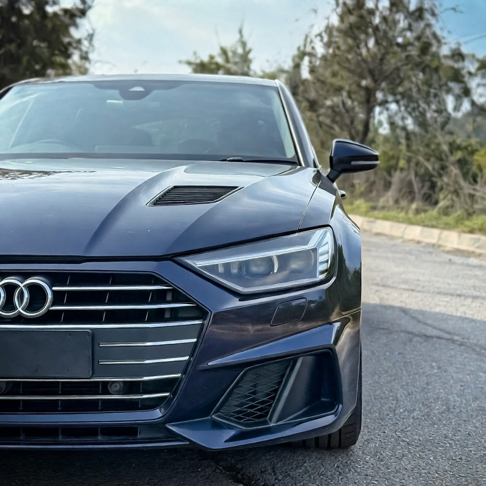 Front view of a blue Audi car on a road with trees in the background